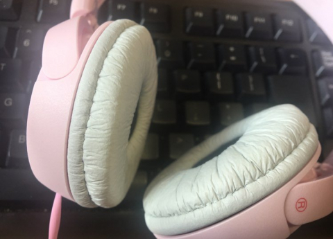biało-różowe słuchawki na tle czarnej klawiatury komputerowej 