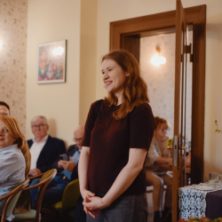 Kobieta stojąca w sali pośród osób